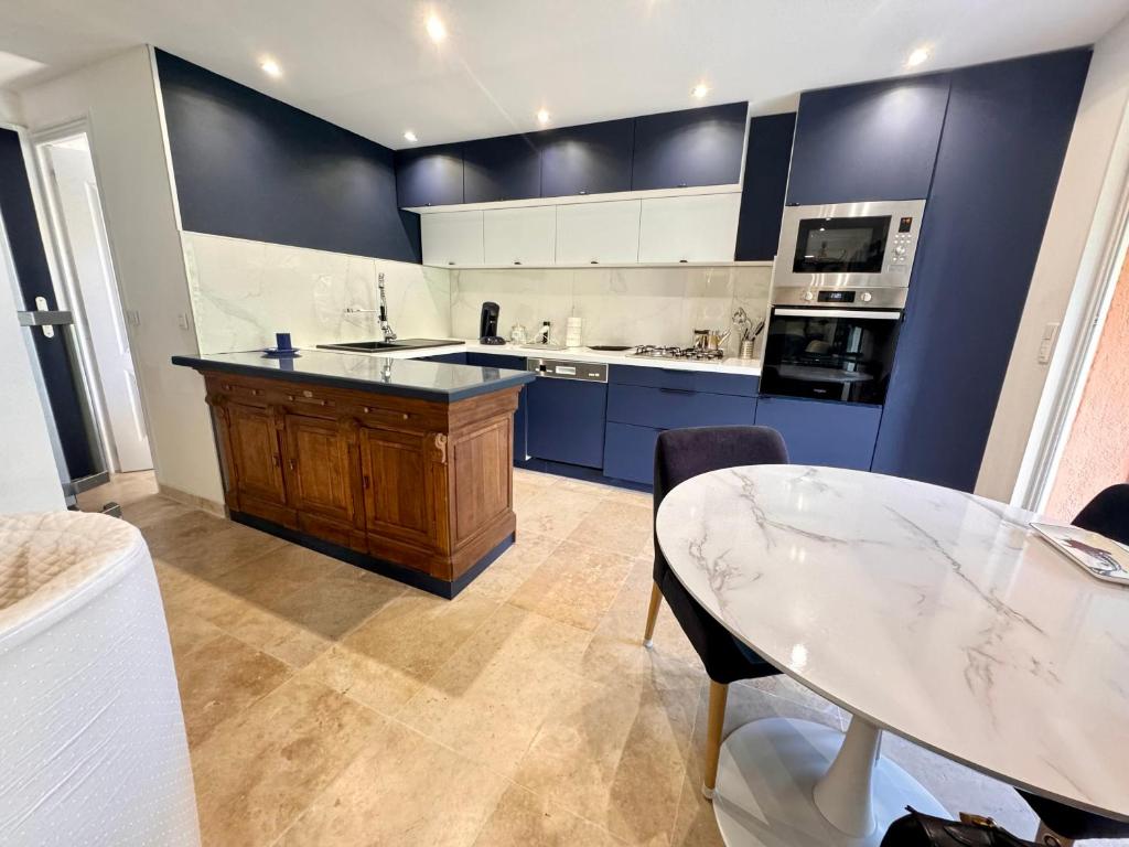 une grande cuisine avec des placards bleus et une table dans l'établissement Appartement Le clos des anges, à Cogolin