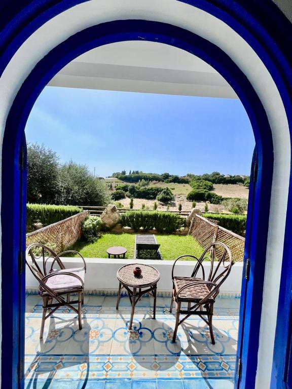 an archway with three chairs and a table on a patio at Dmina House in Asilah