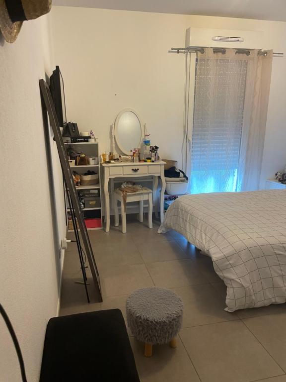 - une chambre avec un lit, une coiffeuse et un miroir dans l'établissement Joli Appartement proche centre ville, à LʼÎle-Rousse