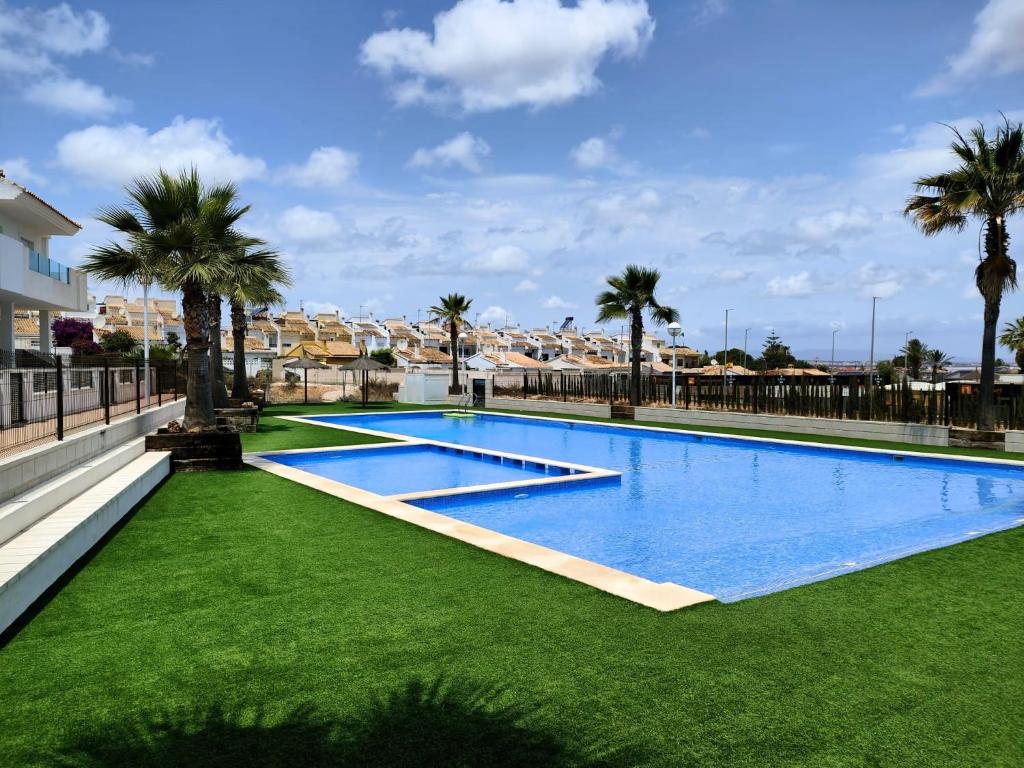 een groot zwembad met groen gras en palmbomen bij Salinas Luxury DaNuria in Torrevieja