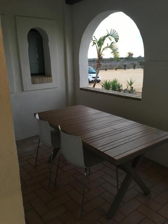 a wooden table and chairs in a room with a window at Hacienda Soto-Hego Haizea in Chiclana de la Frontera