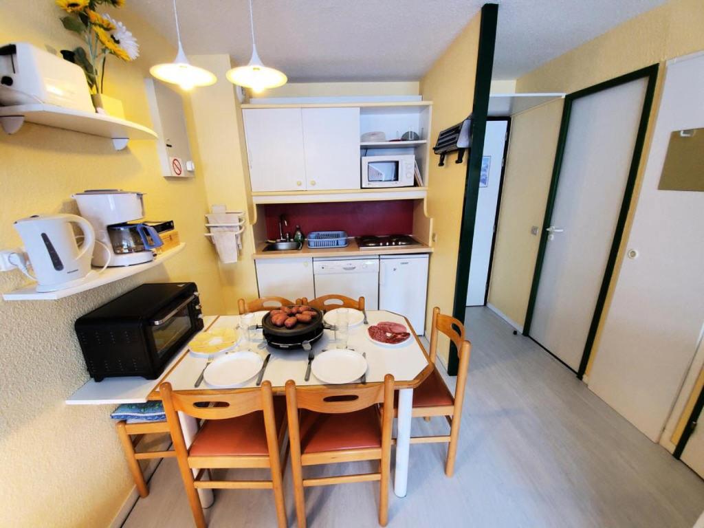 une petite cuisine avec une table et des chaises dans une pièce dans l'établissement Résidence LE DE 3 - Studio pour 4 Personnes MAE-9784, à Aime La Plagne