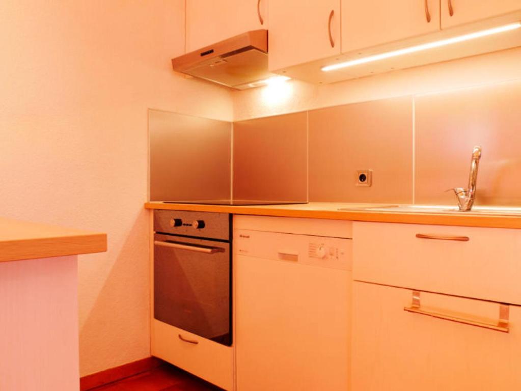 une cuisine avec des armoires blanches, un évier et une cuisinière dans l'établissement Résidence LES ROCHES ROUGES - 2 Pièces pour 7 Personnes MAE-0014, à Aime La Plagne