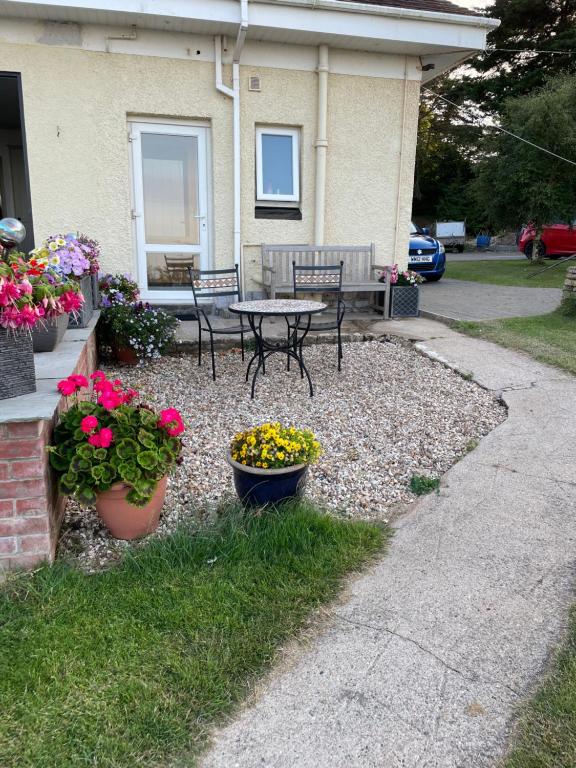 a patio with a table and chairs and flowers at The Stoep in Paignton