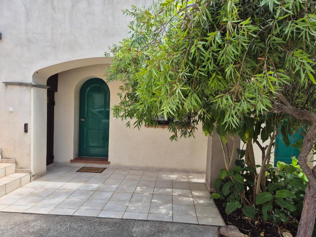 une porte verte sur un bâtiment avec un arbre dans l'établissement Joli appartement climatisé avec terrasse à moin 10 minutes à pieds de la plage, à Calvi