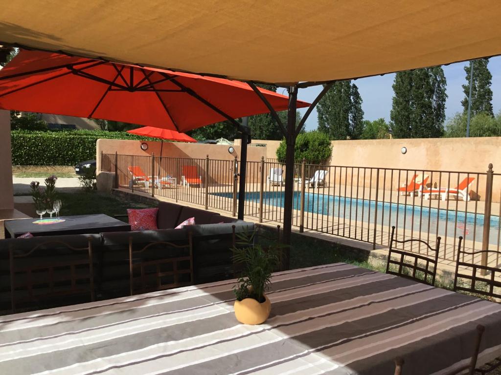 une terrasse avec une table et des parasols à côté d'une piscine dans l'établissement les couleurs du sud, à Aix-en-Provence