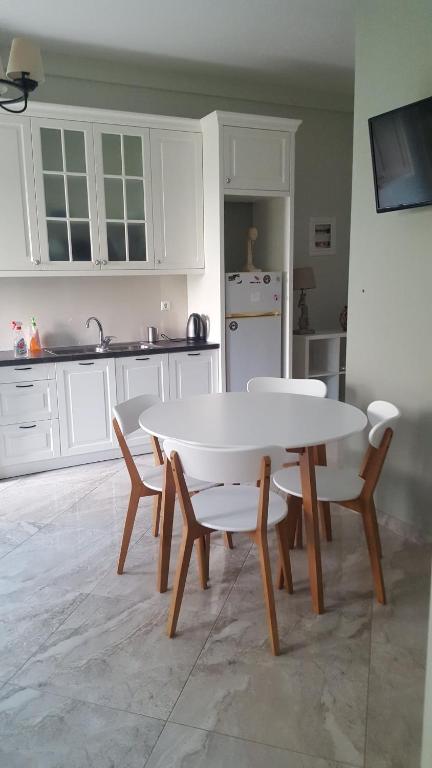 a kitchen with a white table and chairs and a table at Peti's Apartment in Prinos