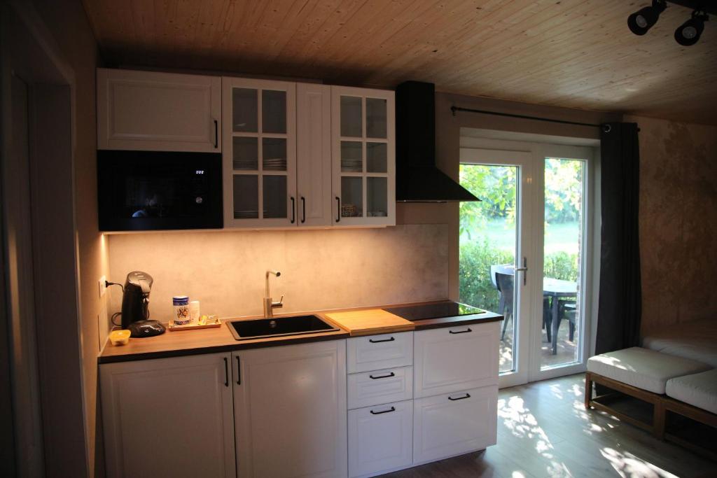 een keuken met witte kasten en een aanrecht bij Summer Lodge - La grange aux quatres saisons - Pairi Daiza in Brugelette