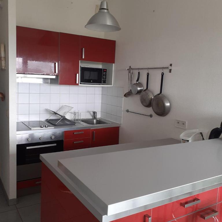 une cuisine avec des armoires rouges et un comptoir blanc dans l'établissement Studio les minimes, à La Rochelle