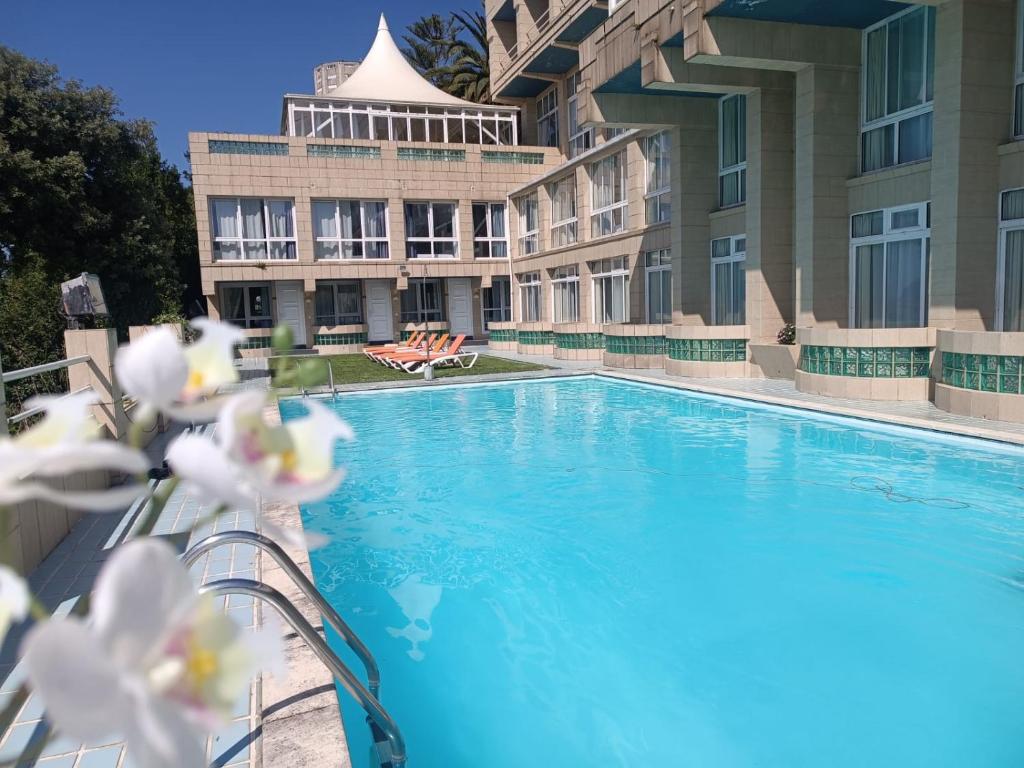 een zwembad voor een gebouw met witte bloemen bij Hotel Miramar Laredo in Laredo