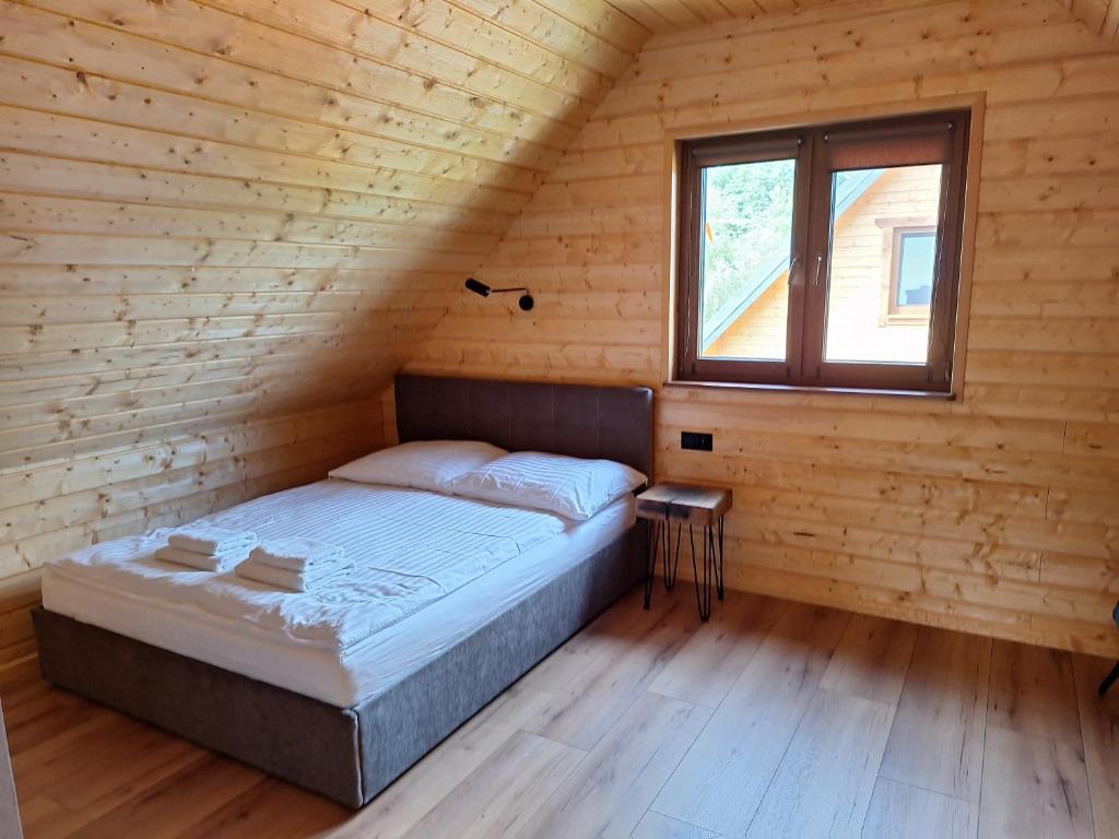 łóżko w drewnianym pokoju z oknem w obiekcie Kamienica House 9 w Wągrowcu