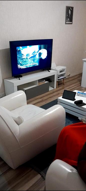 Il comprend un salon doté d'un canapé blanc et d'une télévision à écran plat. dans l'établissement Caen la mer, à Caen