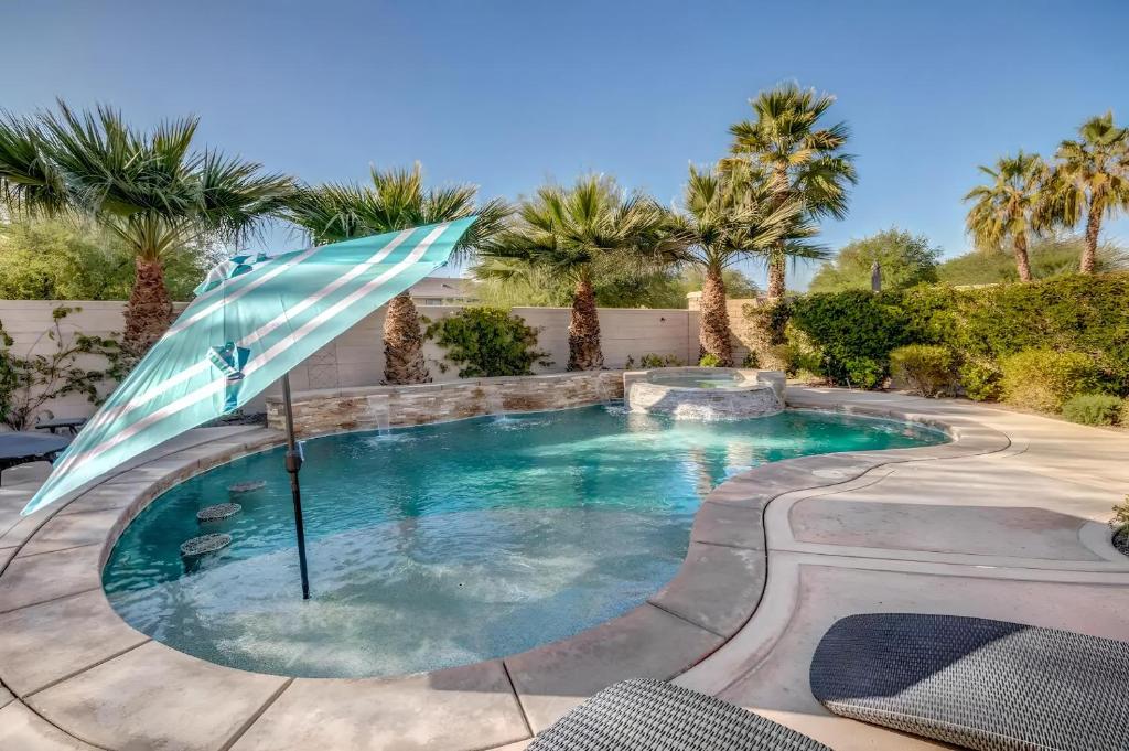 a swimming pool with an umbrella and palm trees at Lux Desert Oasis w saltwater pool near Coachella in Indio