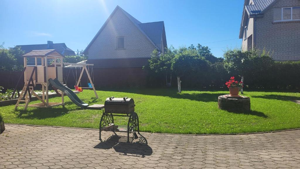 a playground with a grill and a swing in a yard at Apartamentai AGNIJA in Kretinga