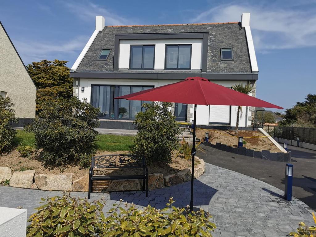 un paraguas rojo frente a una casa en T3-Vue sur ocean - Pieds dans l'eau-Terasse-jardin-Parking gratuit, en Batz-sur-Mer