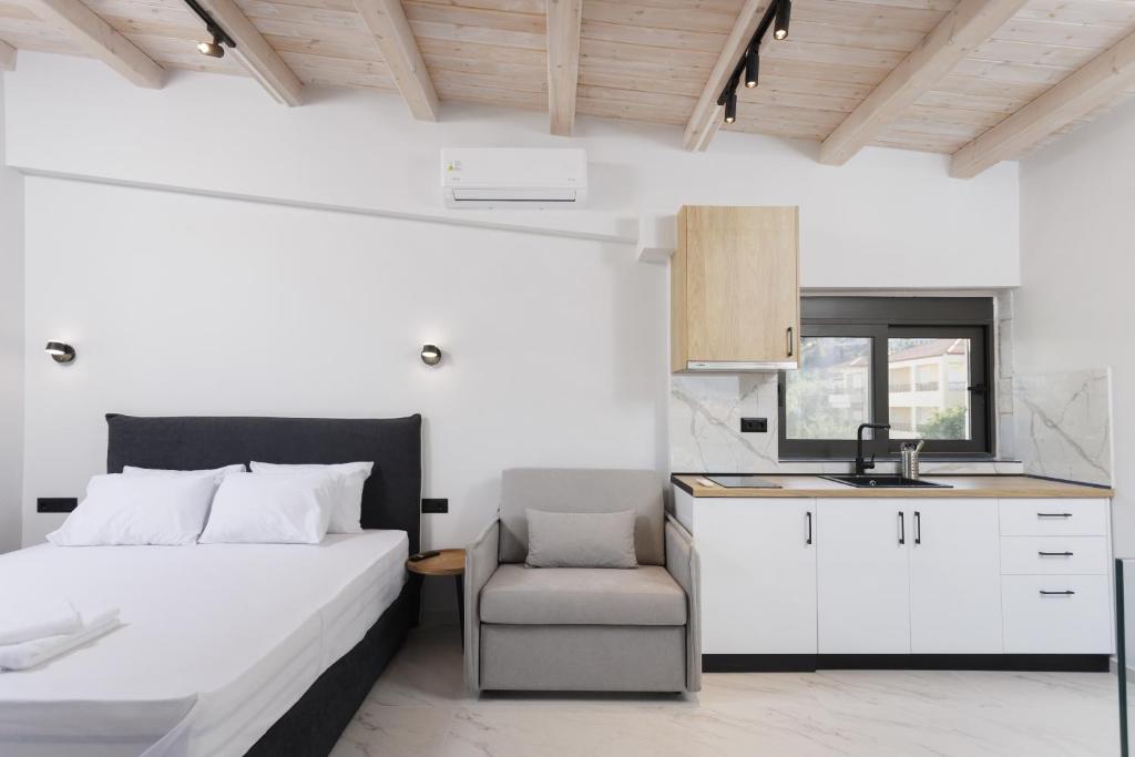 a bedroom with a bed and a chair and a kitchen at Rigas Boutique Rooms in Pefkohori