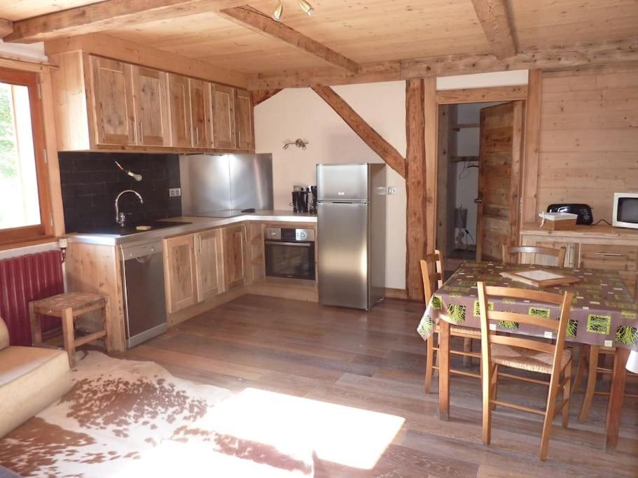 une cuisine avec une table et un réfrigérateur en acier inoxydable dans l'établissement Premier étage d'une ferme rénovée, à Passy