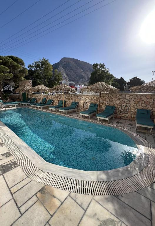 a swimming pool with chairs and a stone wall at Santa Magia in Kamari