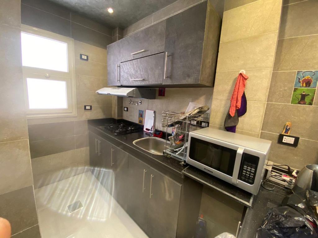 a small kitchen with a microwave and a sink at Villa in Stella Heights - North Coast in El Alamein