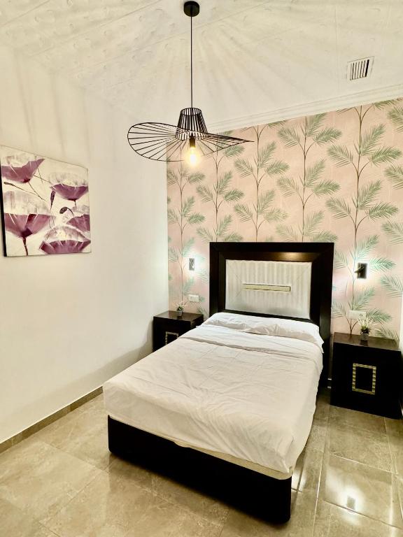 a bedroom with a large bed and a chandelier at Suite la Bella in Torre del Mar