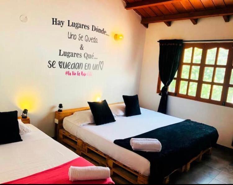 two beds in a room with a writing on the wall at La Vie En Rose CTG in Cartagena de Indias