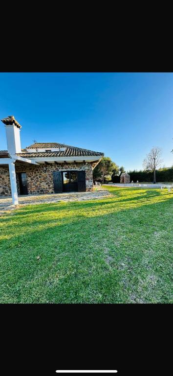 a stone building with a grass field in front of it at Villa Natalia in La Zarzuela