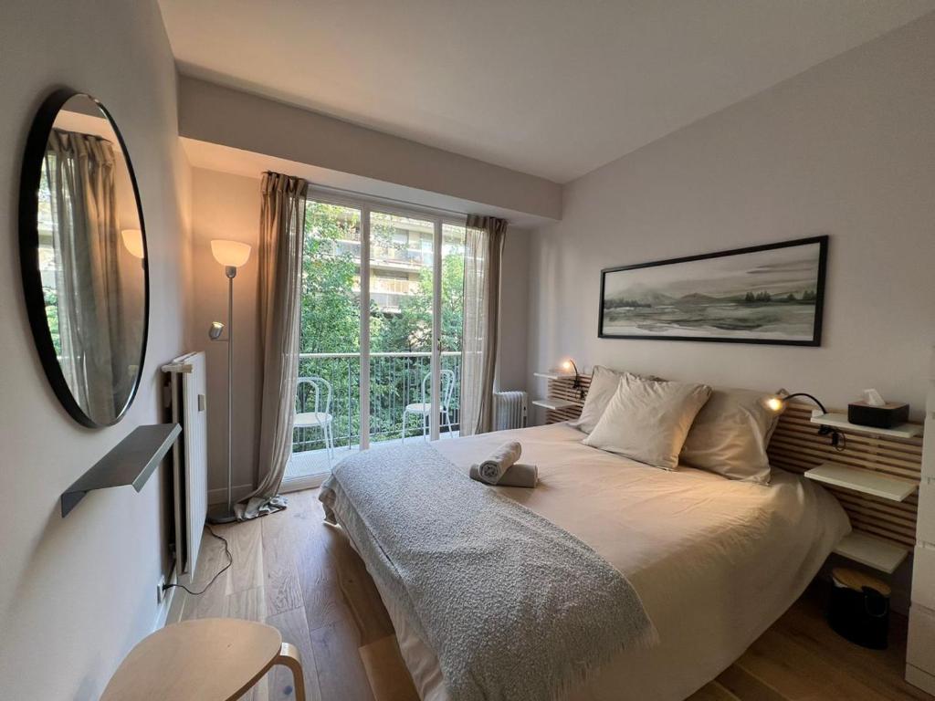 une chambre avec un grand lit et une grande fenêtre dans l'établissement Parisian Charm Close Trocadero, à Paris
