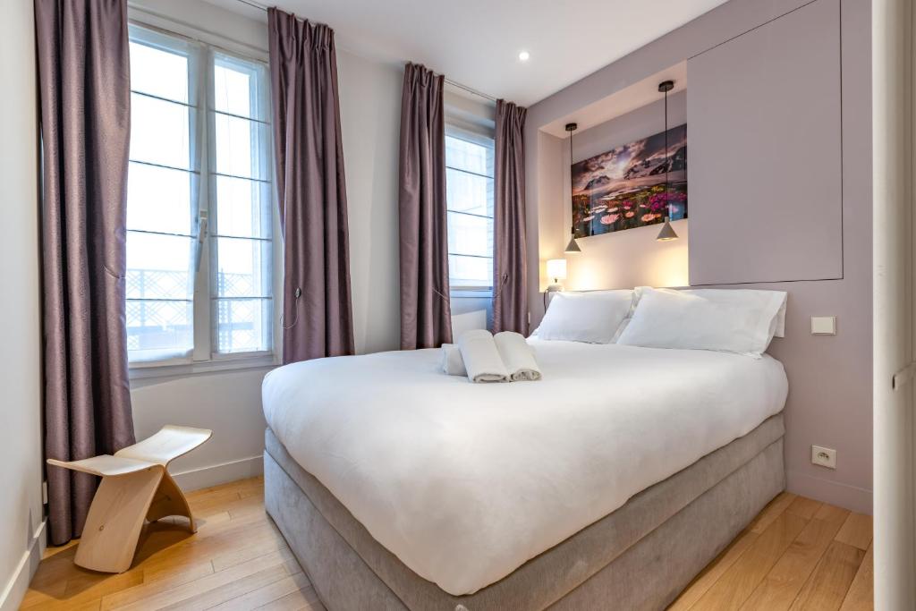 - une chambre avec un grand lit blanc et des fenêtres dans l'établissement Appartement Cosy au cœur du Triangle d Or avec Climatisation, à Paris