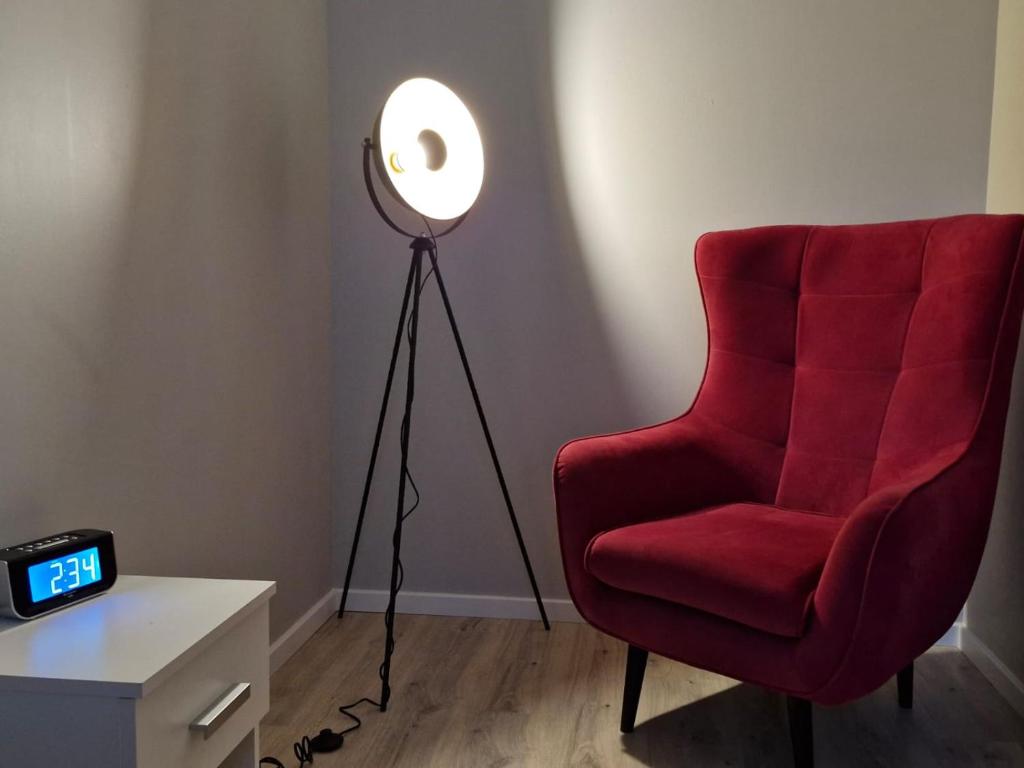 eine Stehlampe und ein roter Stuhl in einem Zimmer in der Unterkunft Apartament Bałtycka & Bike Room in Kołobrzeg