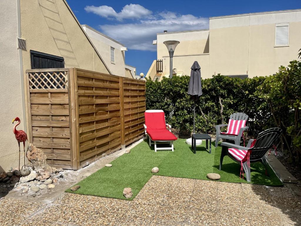 un jardin miniature avec des chaises et un parasol dans l'établissement T3 Rénové Climatisé RDJ - Proche Plage - Parking - Animaux OK - FR-1-799-5, au Barcarès