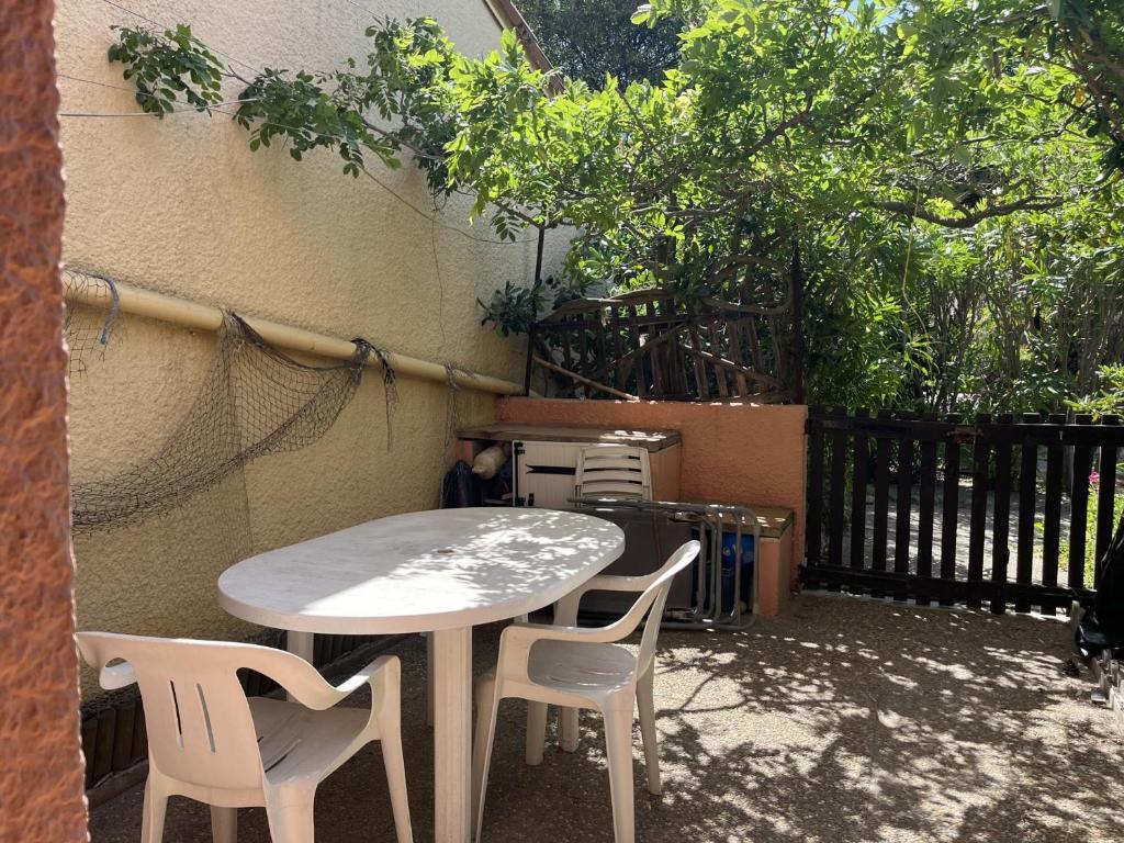 une table et des chaises installées à côté d'un bâtiment dans l'établissement Charmant T3 climatisé en RDC, terrasse fleurie, idéal famille, 6P, proche plage, parking inclus - FR-1-799-18, au Barcarès