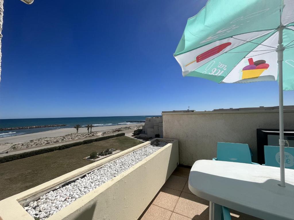 - un balcon avec un parasol et la plage dans l'établissement Studio lumineux face mer avec terrasse et parking, proche port et commerces, 4P - FR-1-799-31, au Barcarès