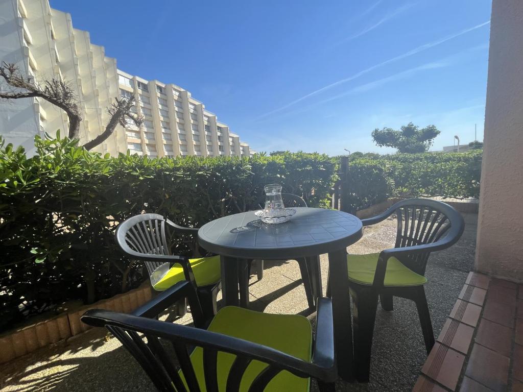 - une table avec 2 chaises et un verre de vin dans l'établissement Le Barcarès - Résidence Front de Mer - T2 Alcôve RDC - 4 Pers - Grande Plage - Parking Inclus - FR-1-799-11, au Barcarès