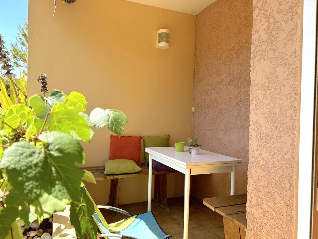 une chambre avec une table blanche et un banc dans l'établissement Appartement 2 pièces coin nuit, balcon sud, proche plage et commerces, garage inclus, 5 couchages - FR-1-251-838, à Bormes-les-Mimosas