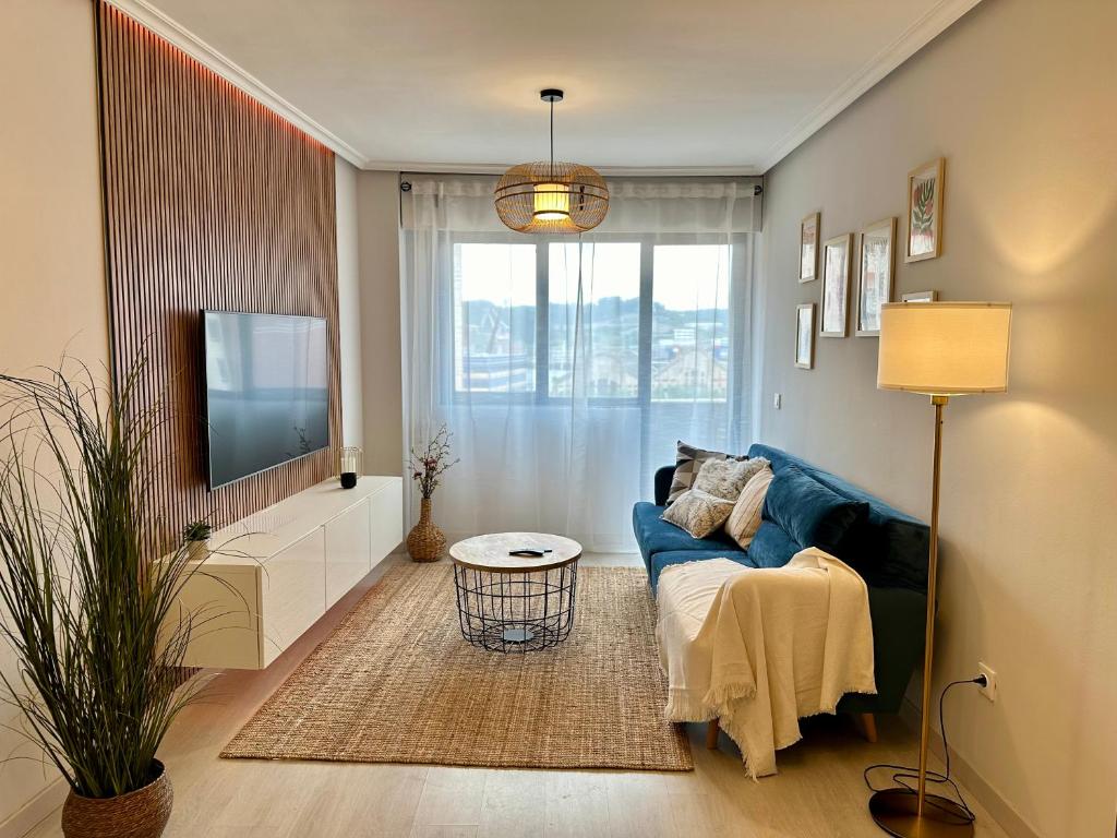 un salon avec un canapé bleu et une télévision dans l'établissement Villa Ana, céntrico y tranquilo, parking incluido, à Avilés