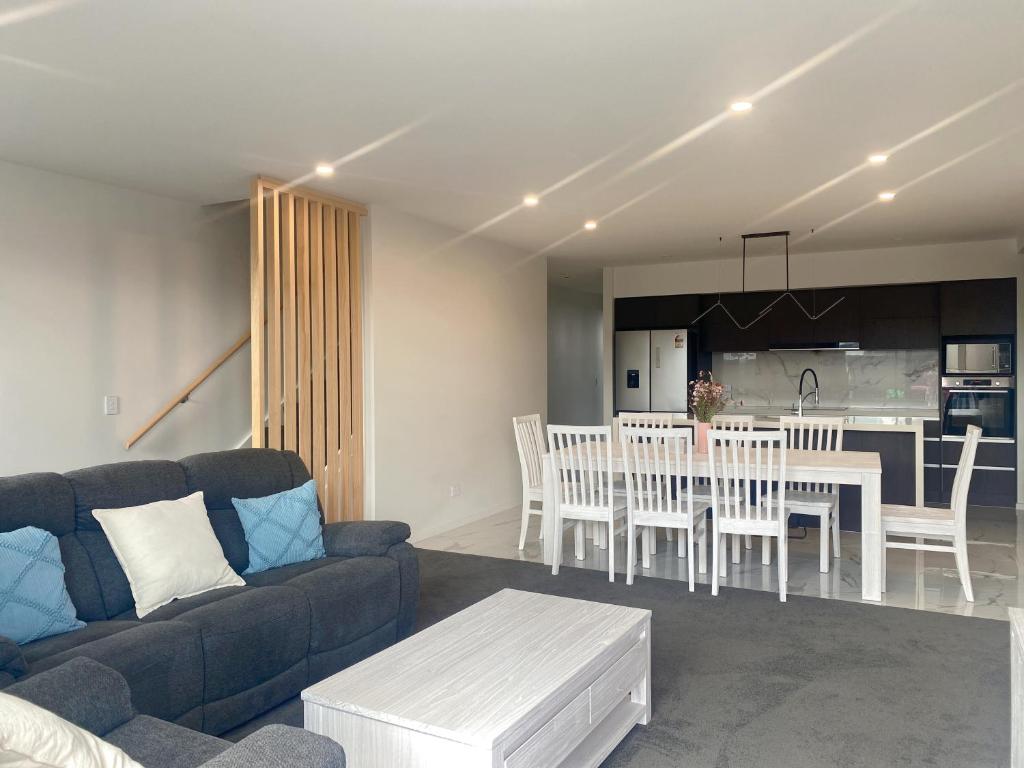 ein Wohnzimmer mit Couch und Tisch und eine Küche in der Unterkunft Modern luxury four bedroom house in Christchurch