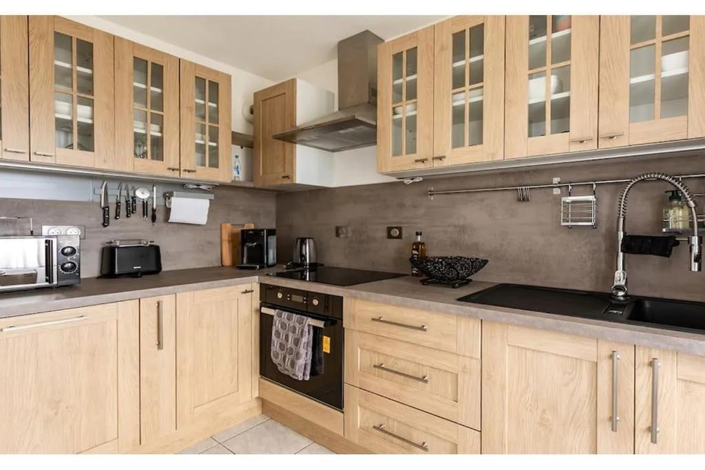 une cuisine avec des armoires en bois et un four à plaques de cuisson dans l'établissement Le Botéro-T3 agréable, 2 chambres, balcon & garage, à Dinard