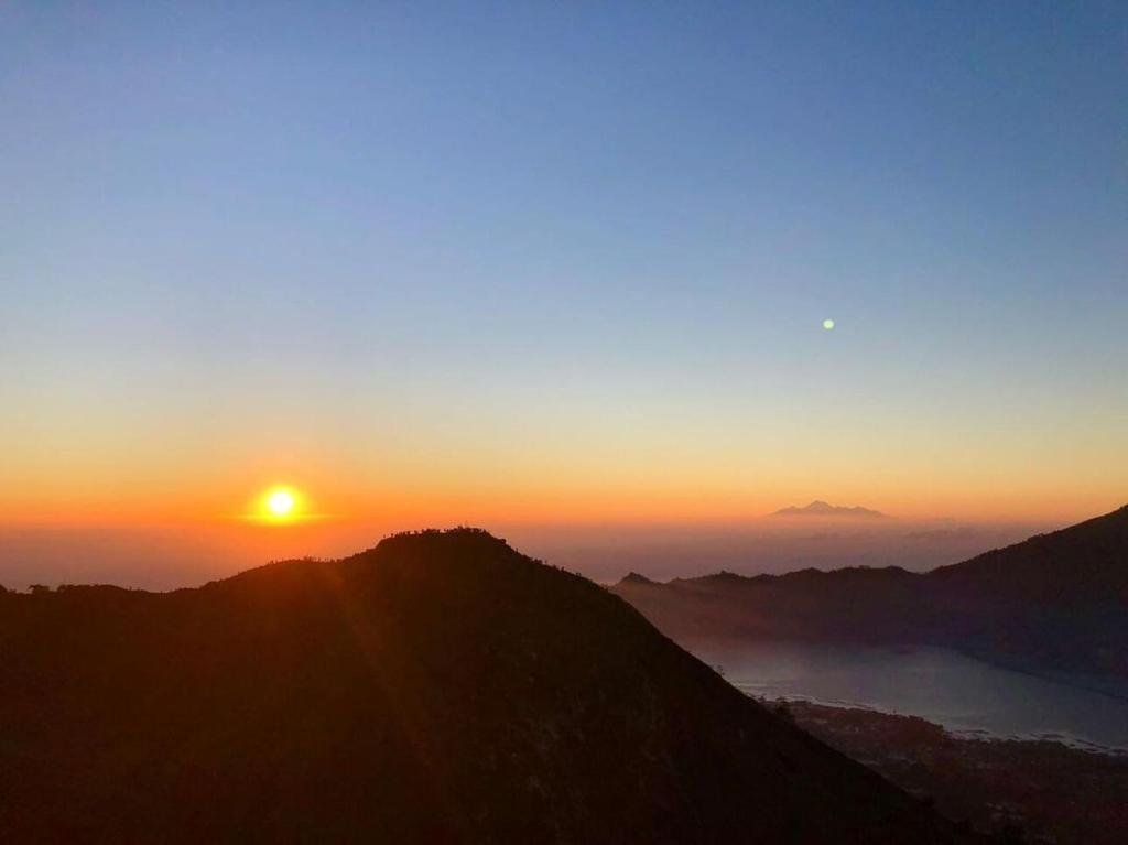 a sun setting on top of a mountain at Mount Batur Sunrise and Sunset Camping in Bangli