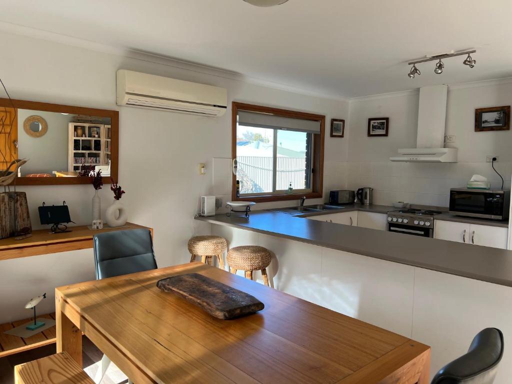a kitchen with a wooden table and a kitchen counter at Lazy Sails Port - Pets welcome inside WiFi in Robe