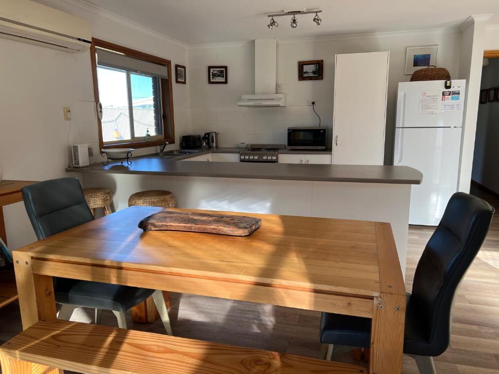 a kitchen with a wooden table and a counter top at Lazy Sails Port - Pets welcome inside WiFi in Robe