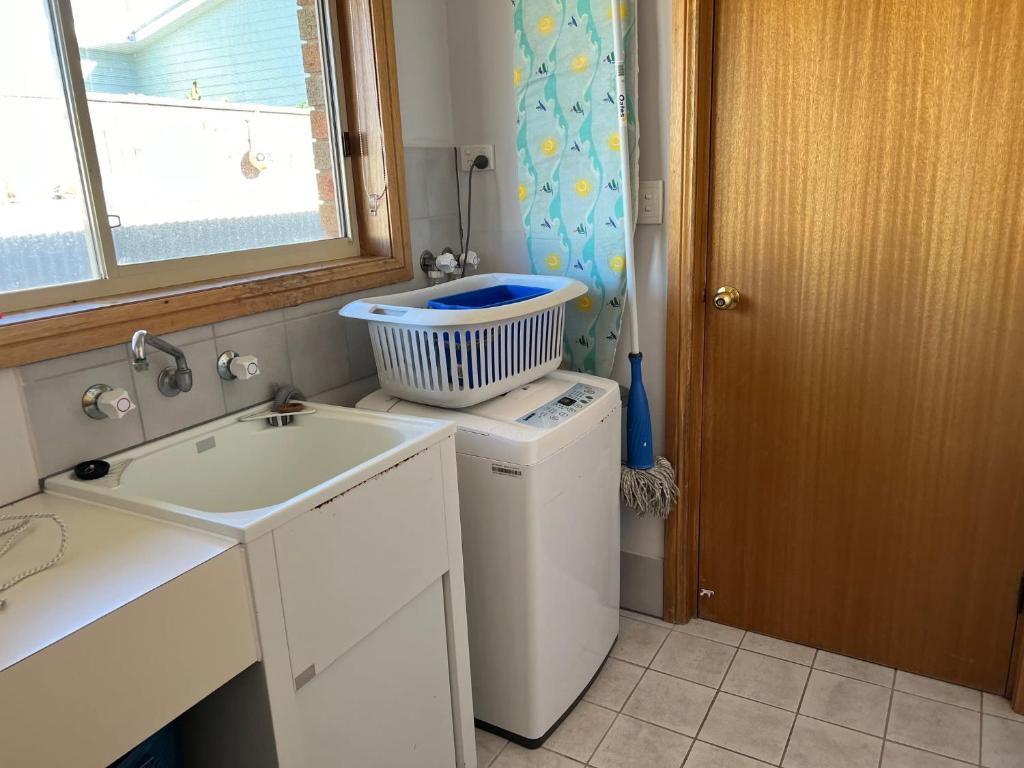 a small kitchen with a sink and a washing machine at Lazy Sails Port - Pets welcome inside WiFi in Robe