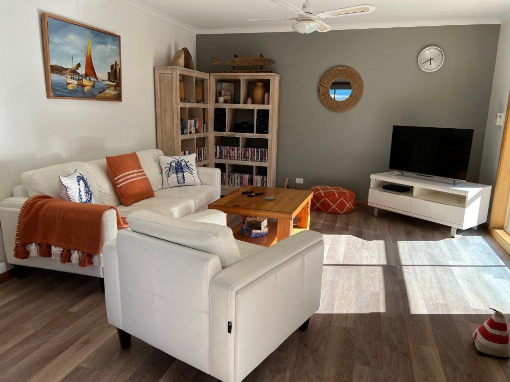 a living room with a white couch and a tv at Lazy Sails Port - Pets welcome inside WiFi in Robe