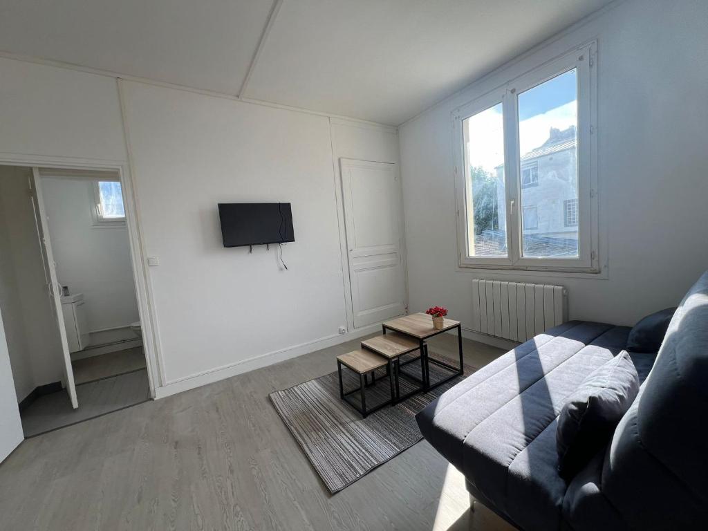 un salon avec un canapé et une télévision dans l'établissement Le Robespierre, à Rouen