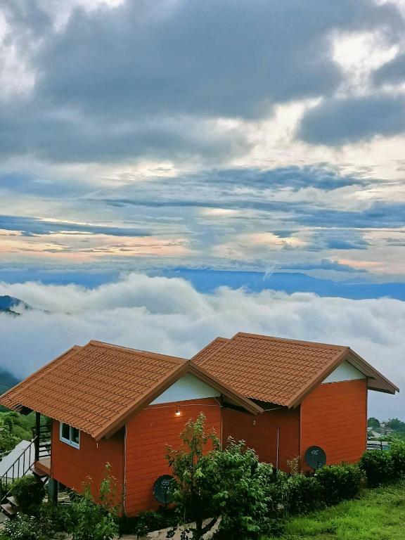 a house with a roof on top of a field at Nuea Tawan at Phu Thap Buek in Ban Tha Kok Hai