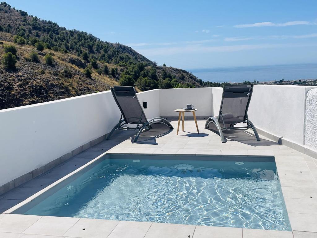 einen Pool auf einem Balkon mit 2 Stühlen und einem Tisch in der Unterkunft Casa Paraiso en Frigiliana in Frigiliana