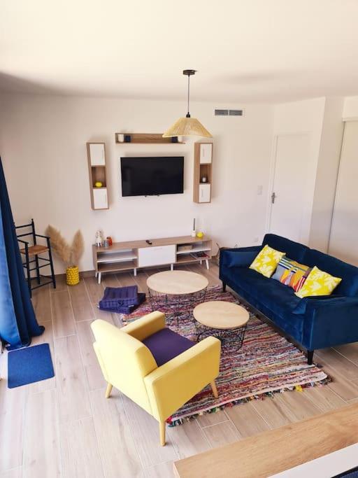 un salon avec un canapé bleu et une télévision dans l'établissement La Riviera - Site du Futuroscope - 3 chambres, à Chasseneuil-du-Poitou