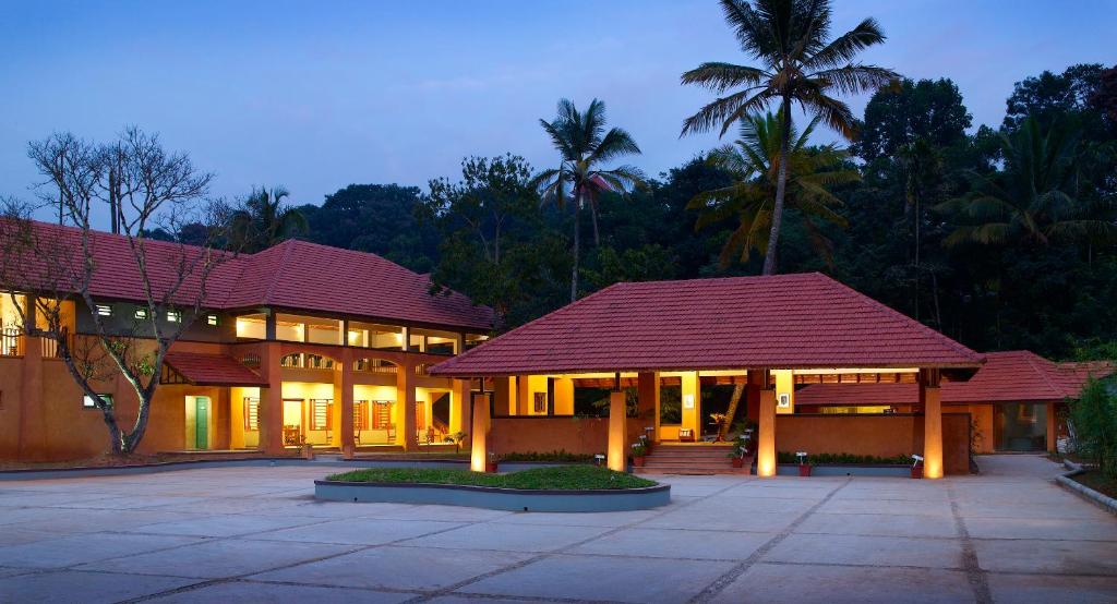 a large building with a red roof and palm trees at Abad Green Forest Thekkady in Thekkady