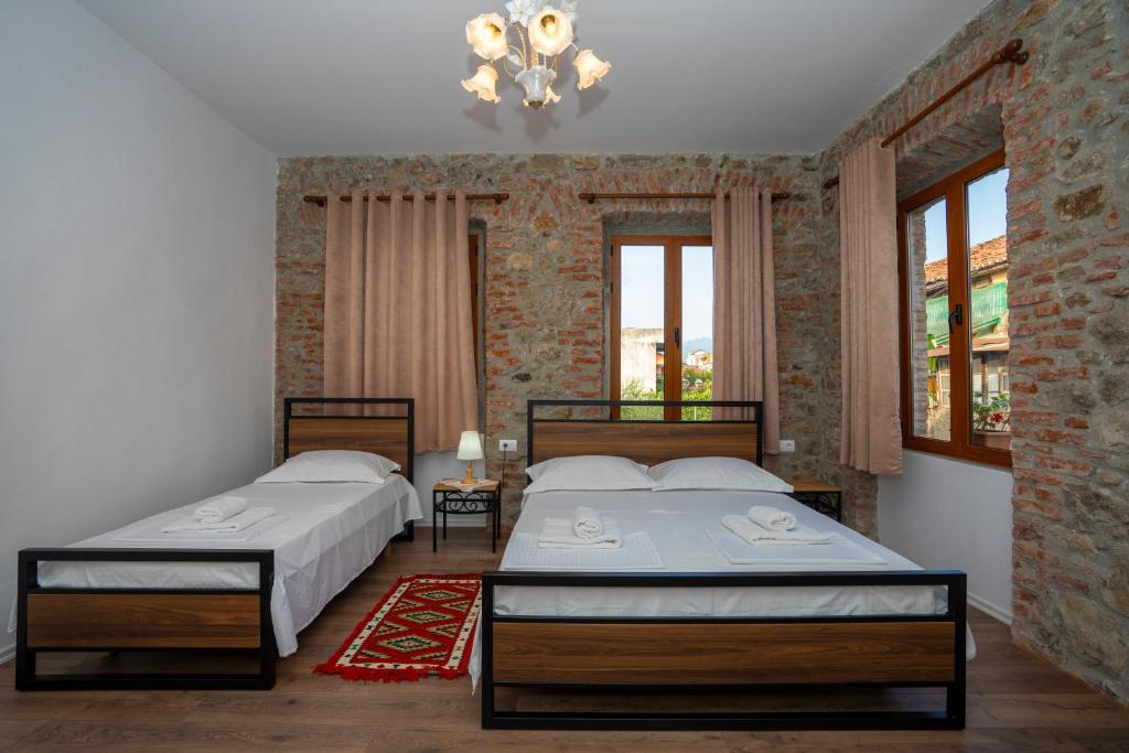two beds in a room with two windows at InTown Guesthouse Shkoder in Shkodër