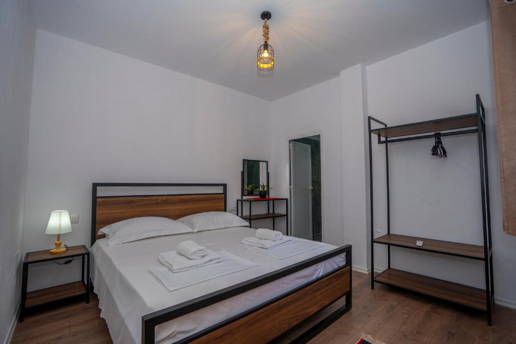 a bedroom with a bed with white sheets and a mirror at InTown Guesthouse Shkoder in Shkodër