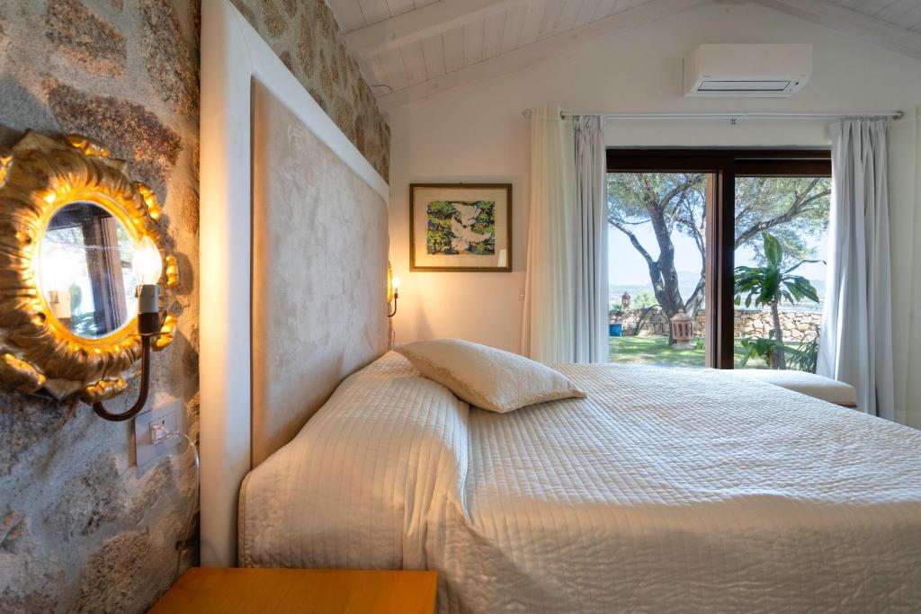 a bedroom with a bed with a mirror and a window at Domus de Rocas Holiday House in Porto Rotondo